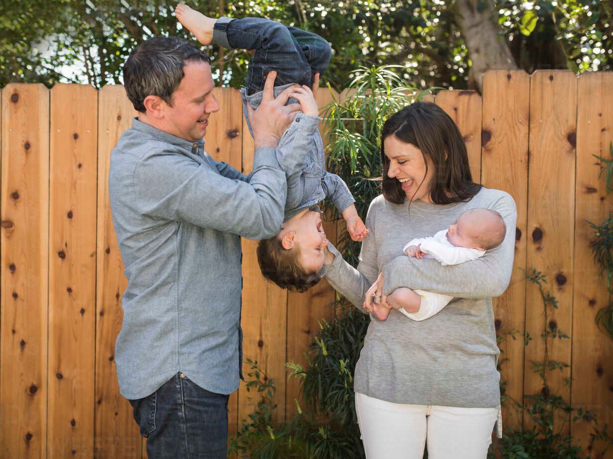 A family is posing for a picture in front of a wooden fence.