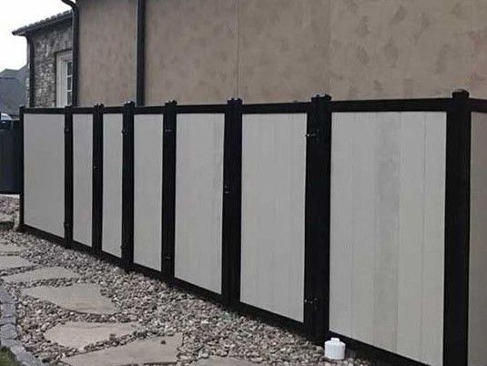 A black and white fence is sitting next to a house.