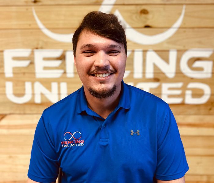 A man in a blue shirt is smiling in front of a sign that says fei ing united