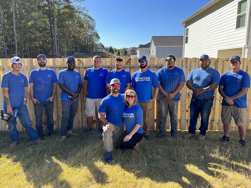 A group of people are posing for a picture in front of a wooden fence.