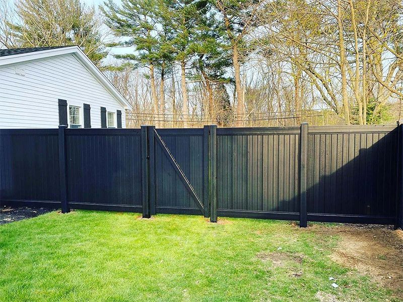 A black fence is in the backyard of a house.