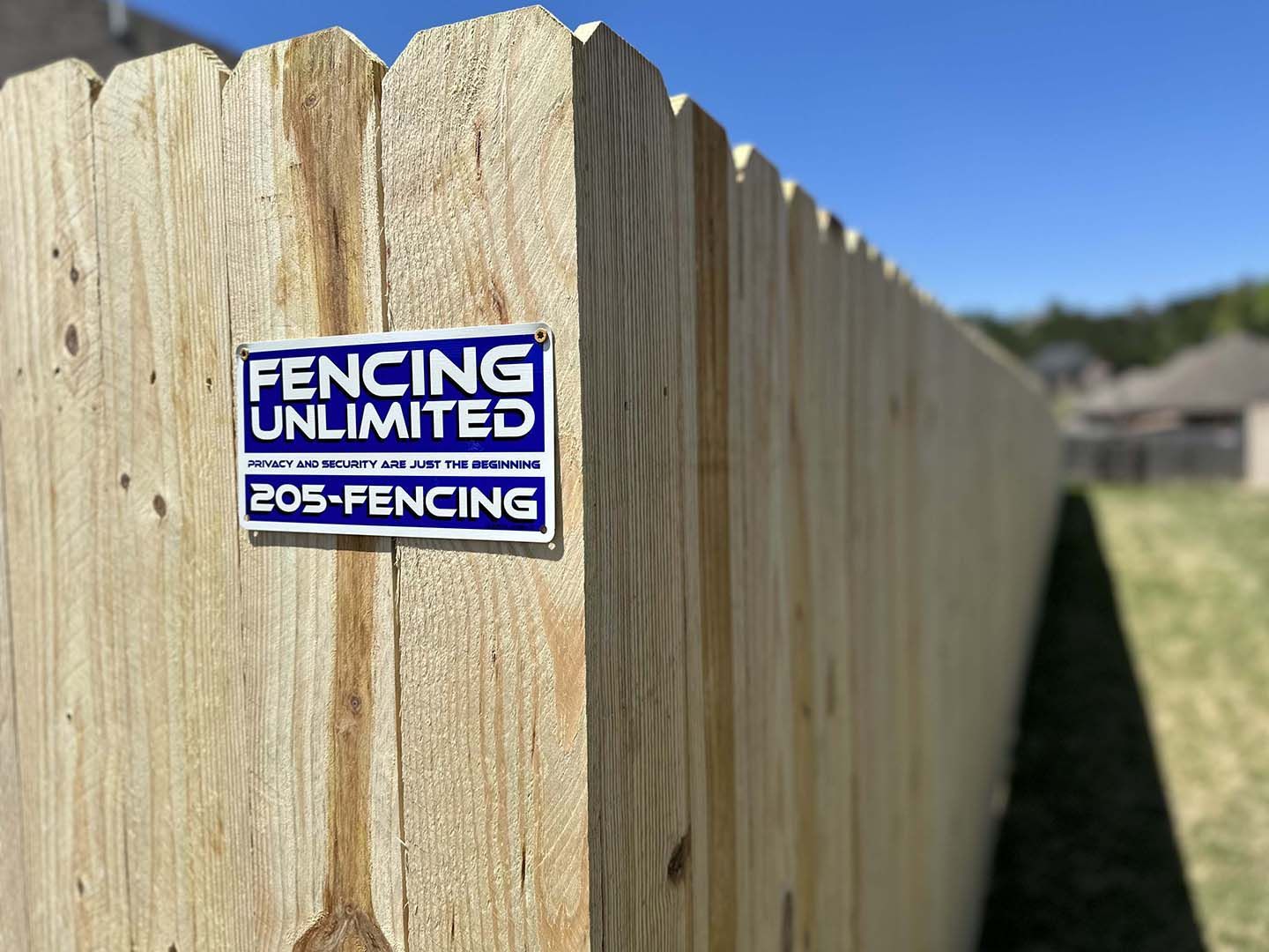 A wooden fence with a sticker on it that says fencing unlimited.