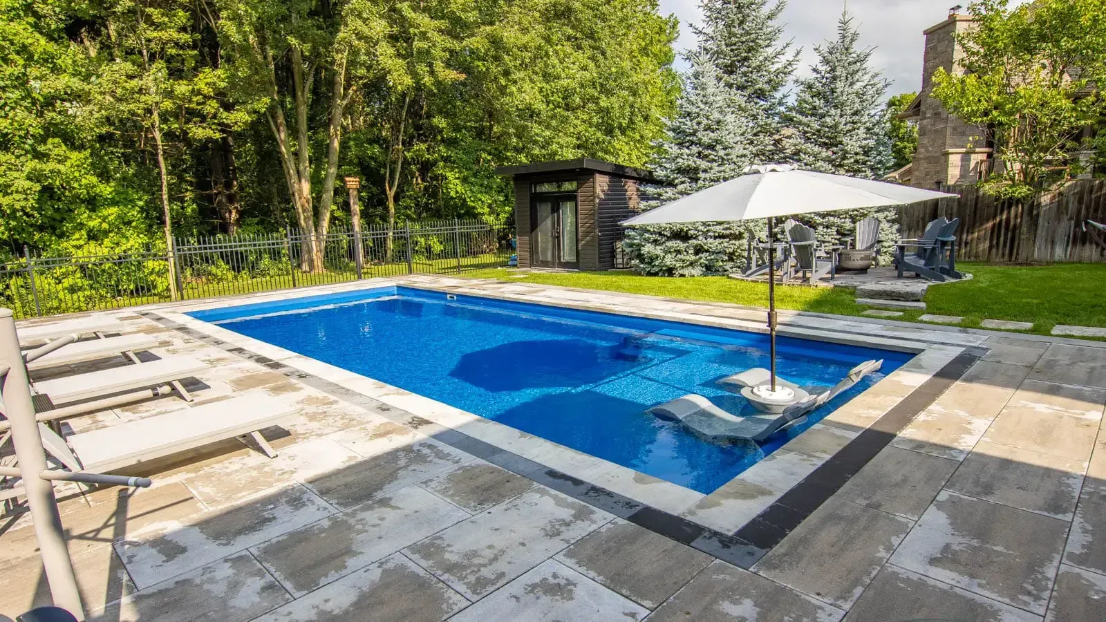 A large swimming pool with a white umbrella in the middle of it.