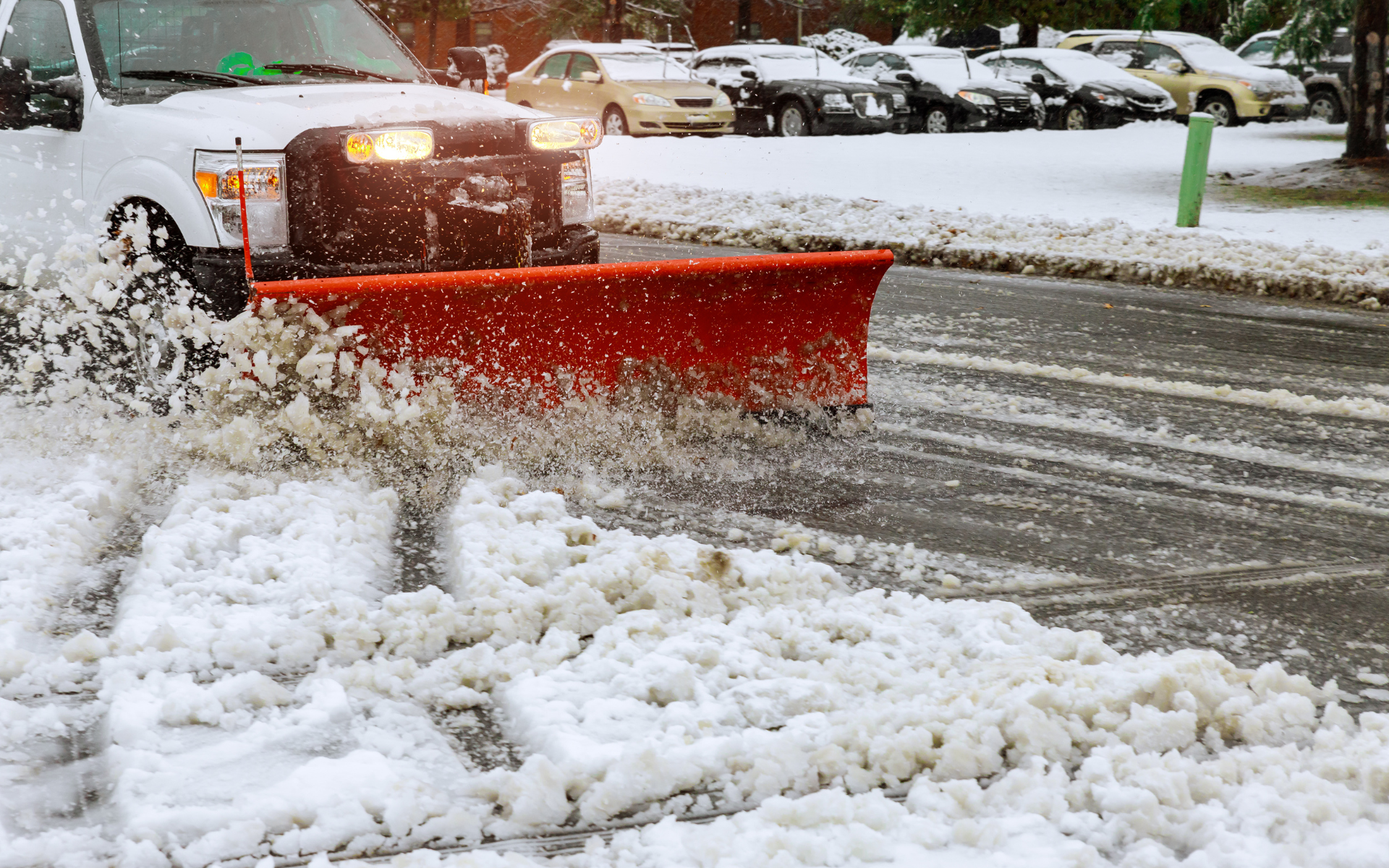 Snow plow on the front of a truck snowplowing a commercial parking lot