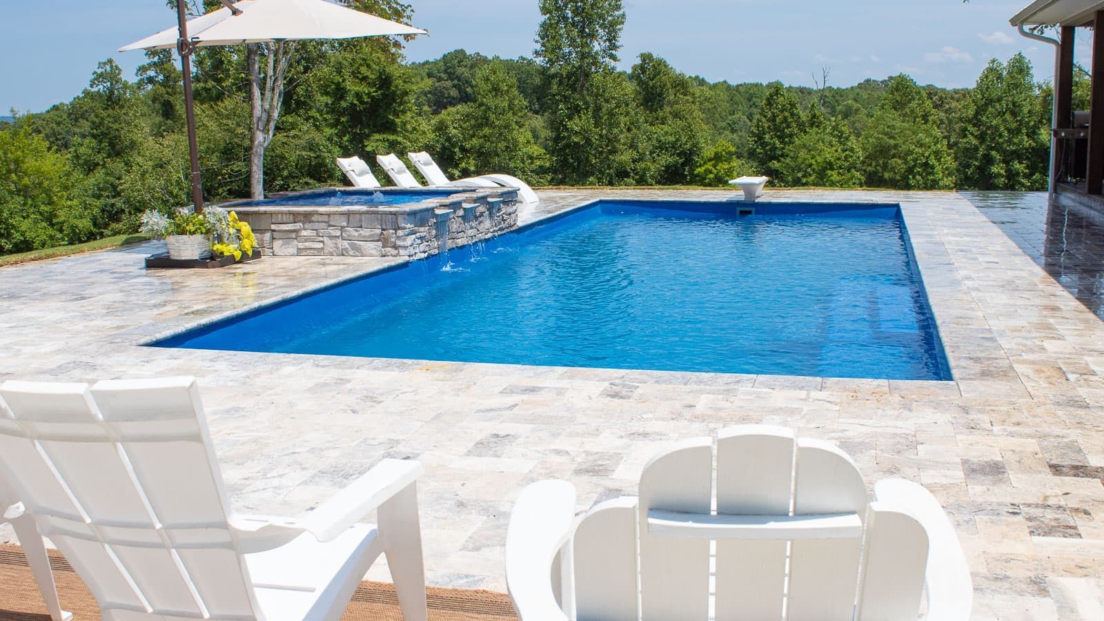 A large swimming pool surrounded by white chairs and umbrellas