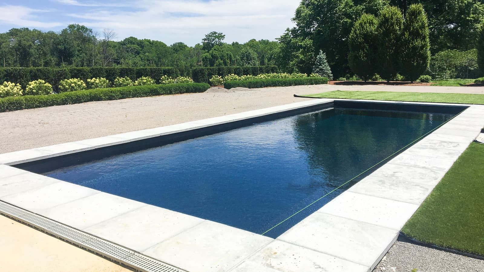 A large swimming pool is surrounded by grass and trees
