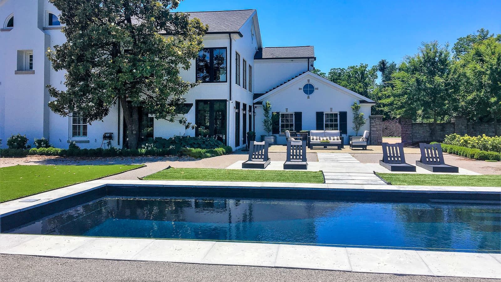 A gorgeous mansion with a large yard featuring the The Celebreation Pool Layout in Volcanic Black Pool Color