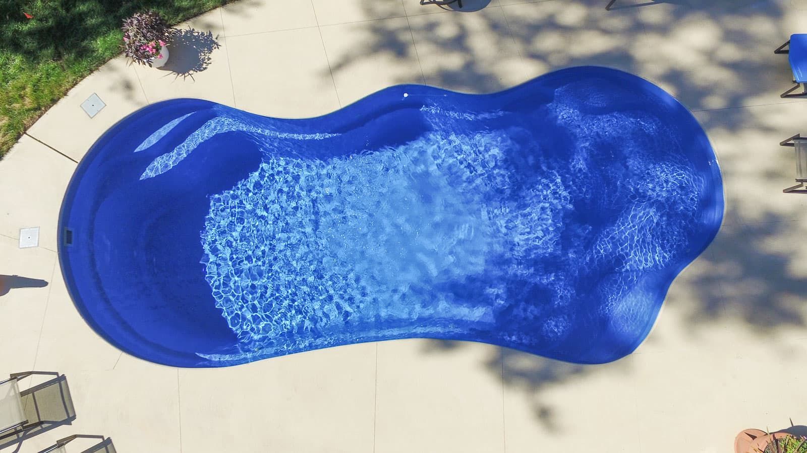 An aerial view of a large blue swimming pool in a backyard.