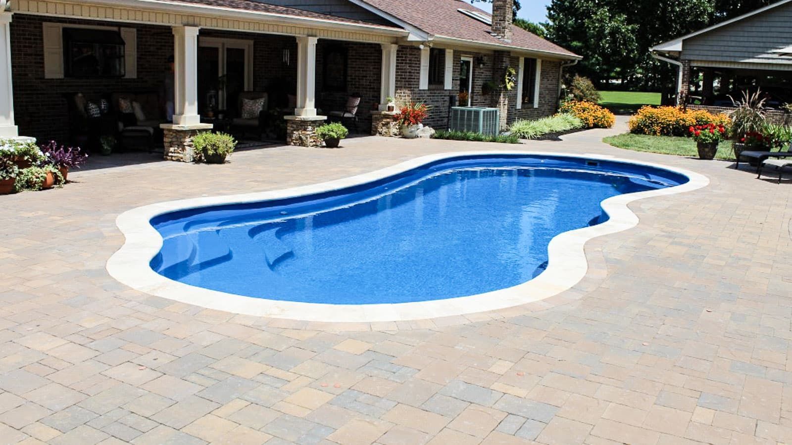 A large swimming pool is in the backyard of a house.
