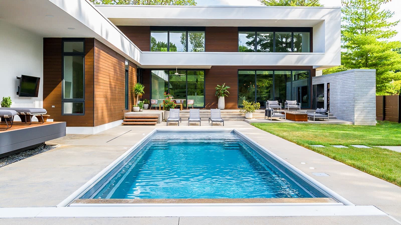 A large swimming pool is in the backyard of a modern house.