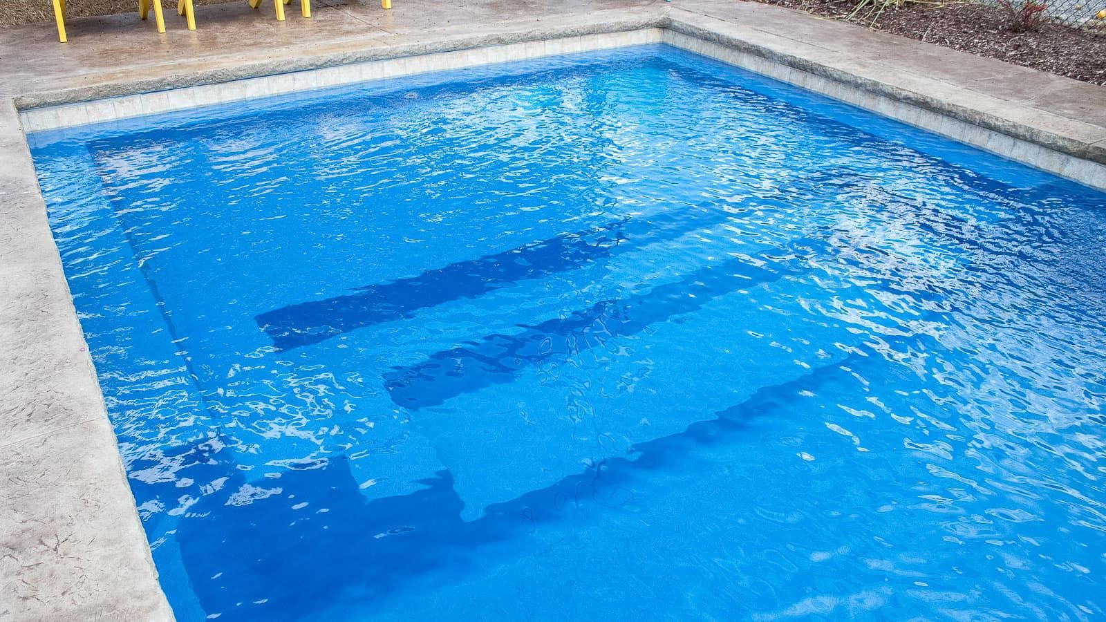 A large swimming pool filled with blue water and steps.