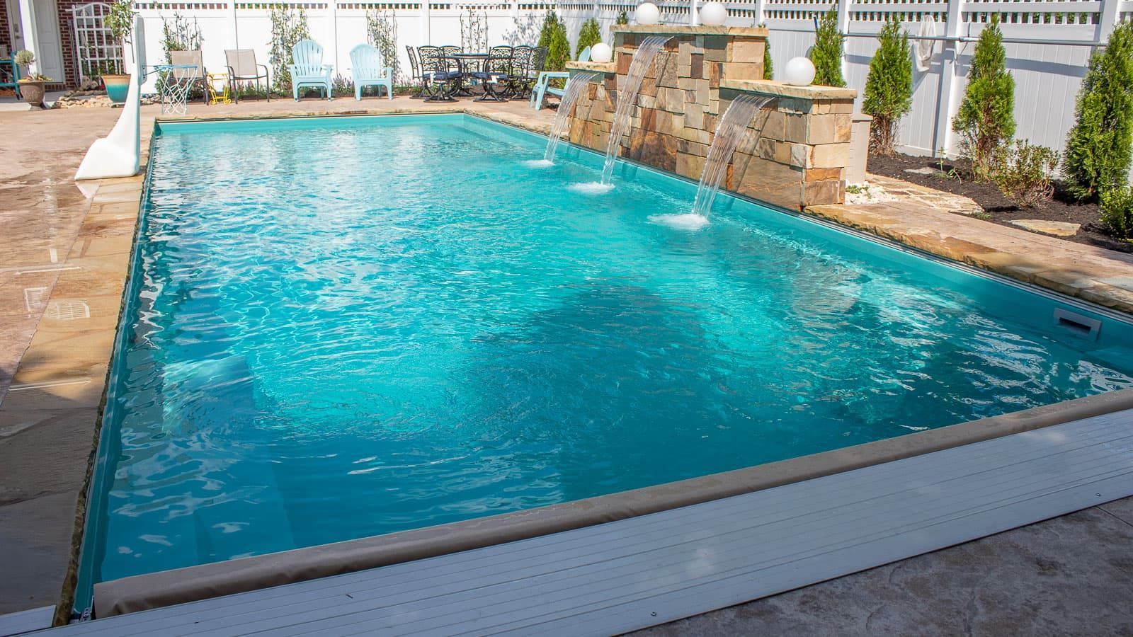 A large swimming pool with a waterfall in the backyard.