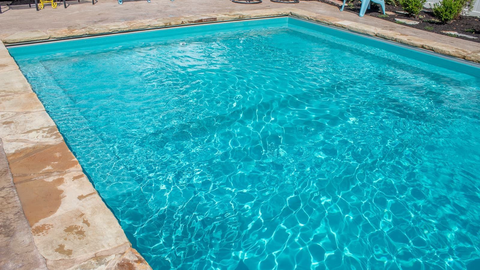 A large swimming pool filled with blue water in a backyard.