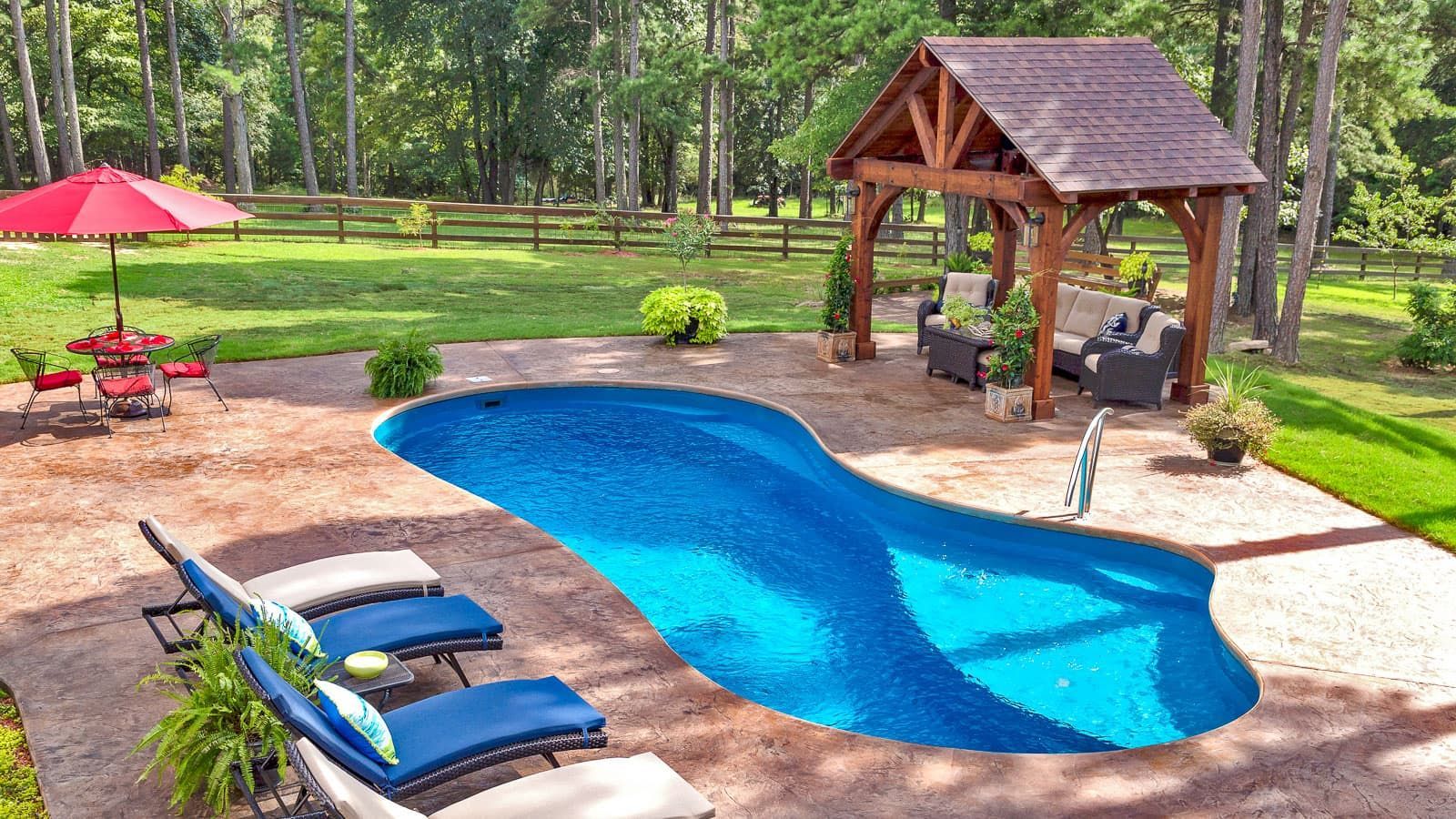 A large swimming pool surrounded by chairs and umbrellas in a backyard.