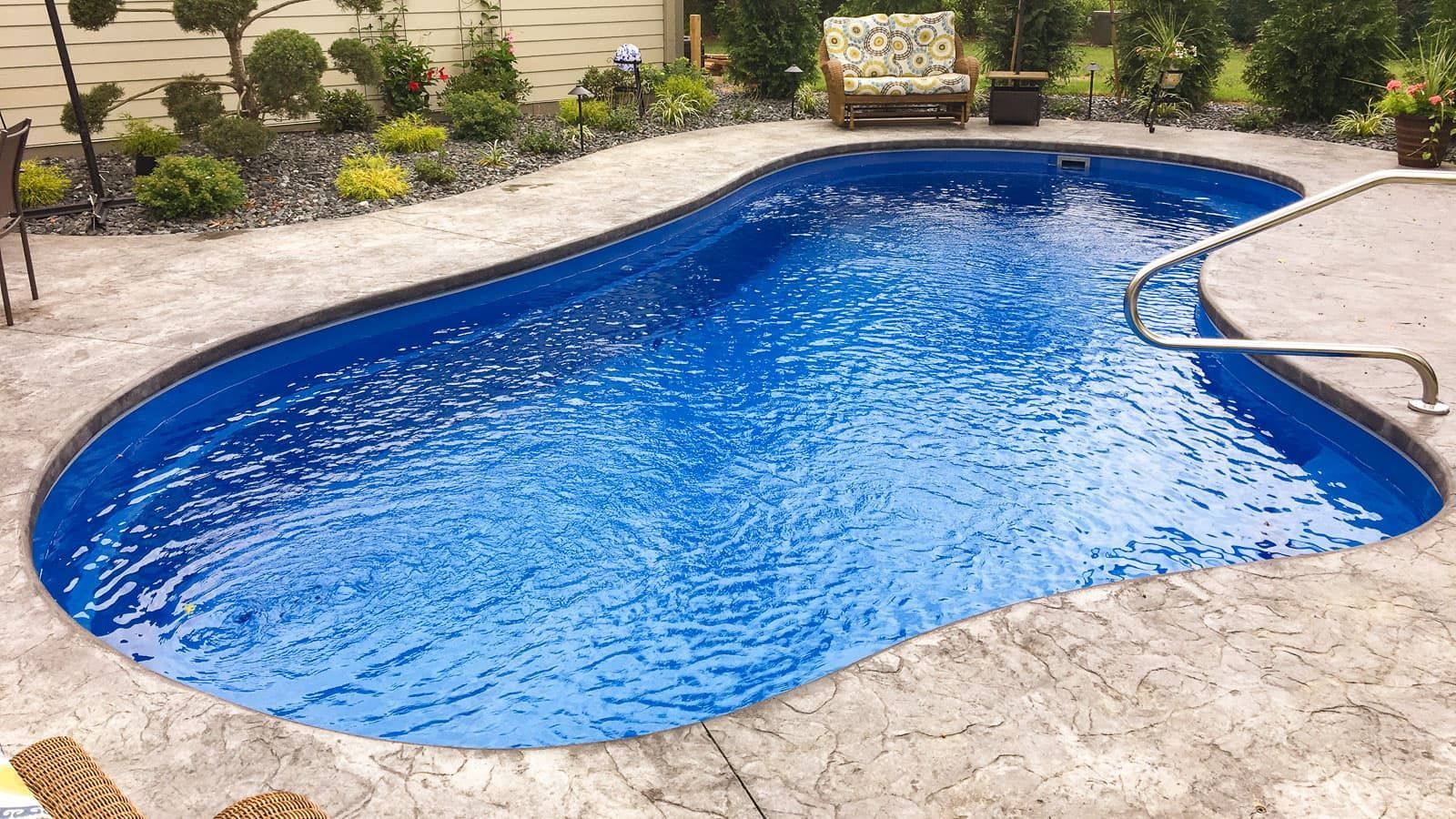 A large blue swimming pool is sitting on top of a concrete patio.