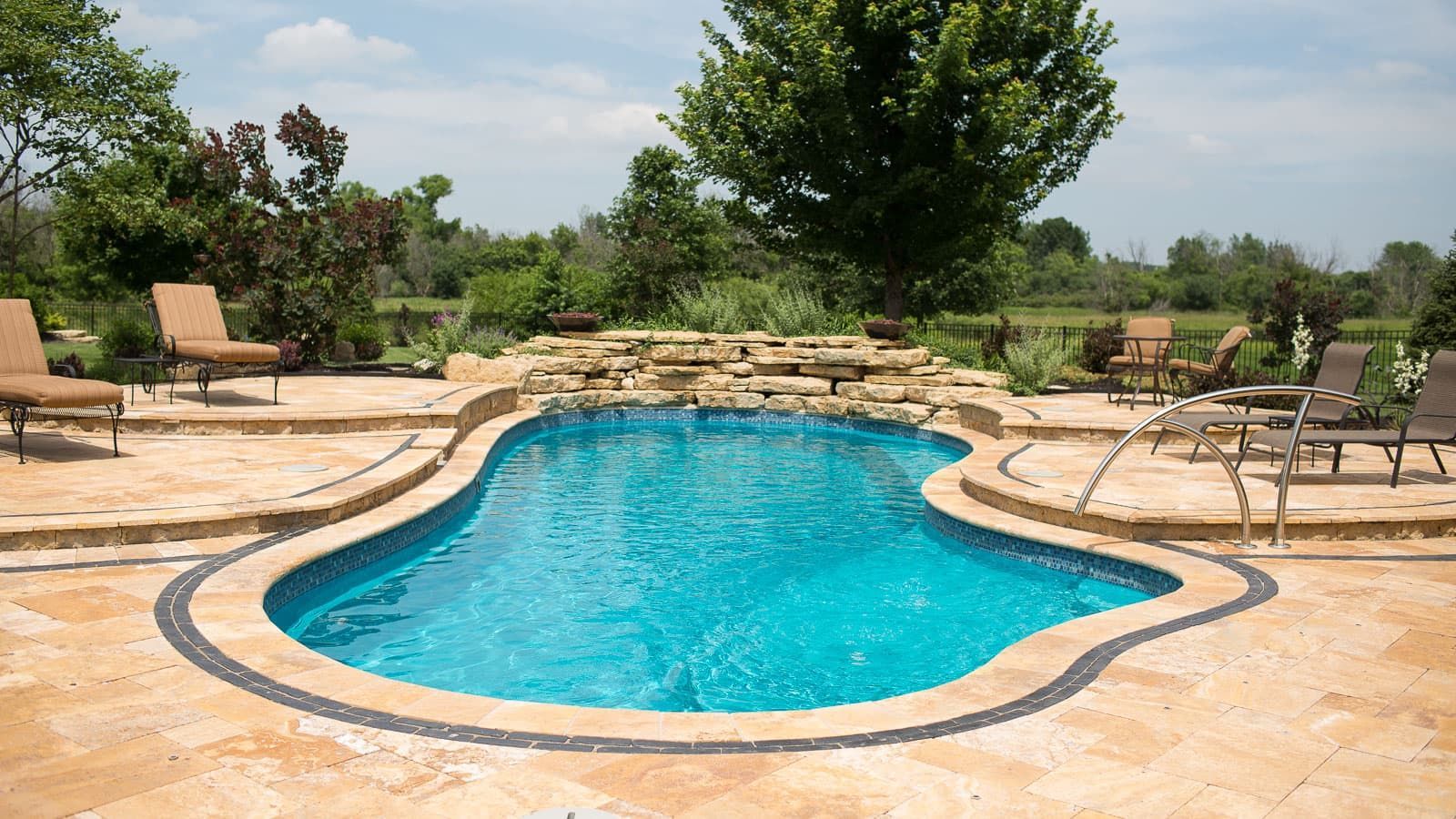 A large swimming pool is surrounded by chairs and a patio.