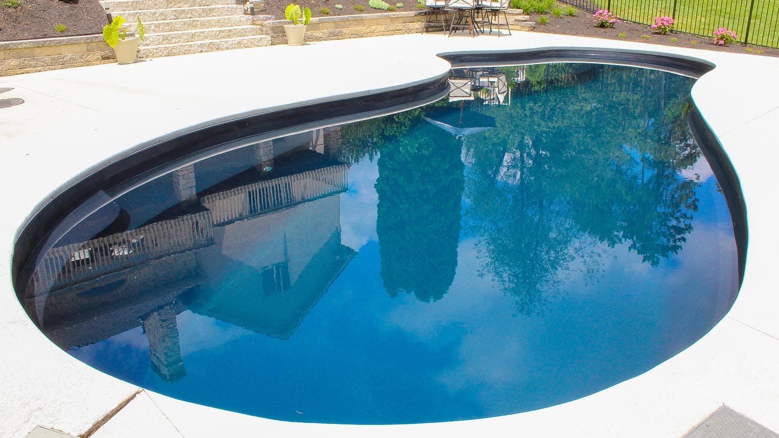 A large swimming pool is sitting on top of a concrete patio.