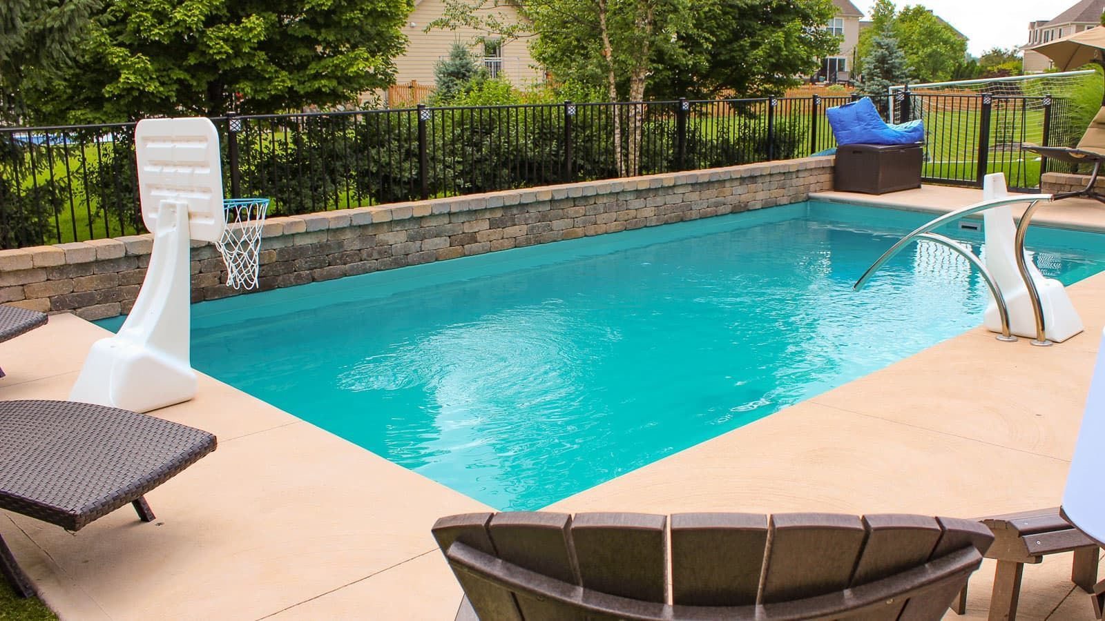 A large swimming pool with a basketball hoop in the backyard.