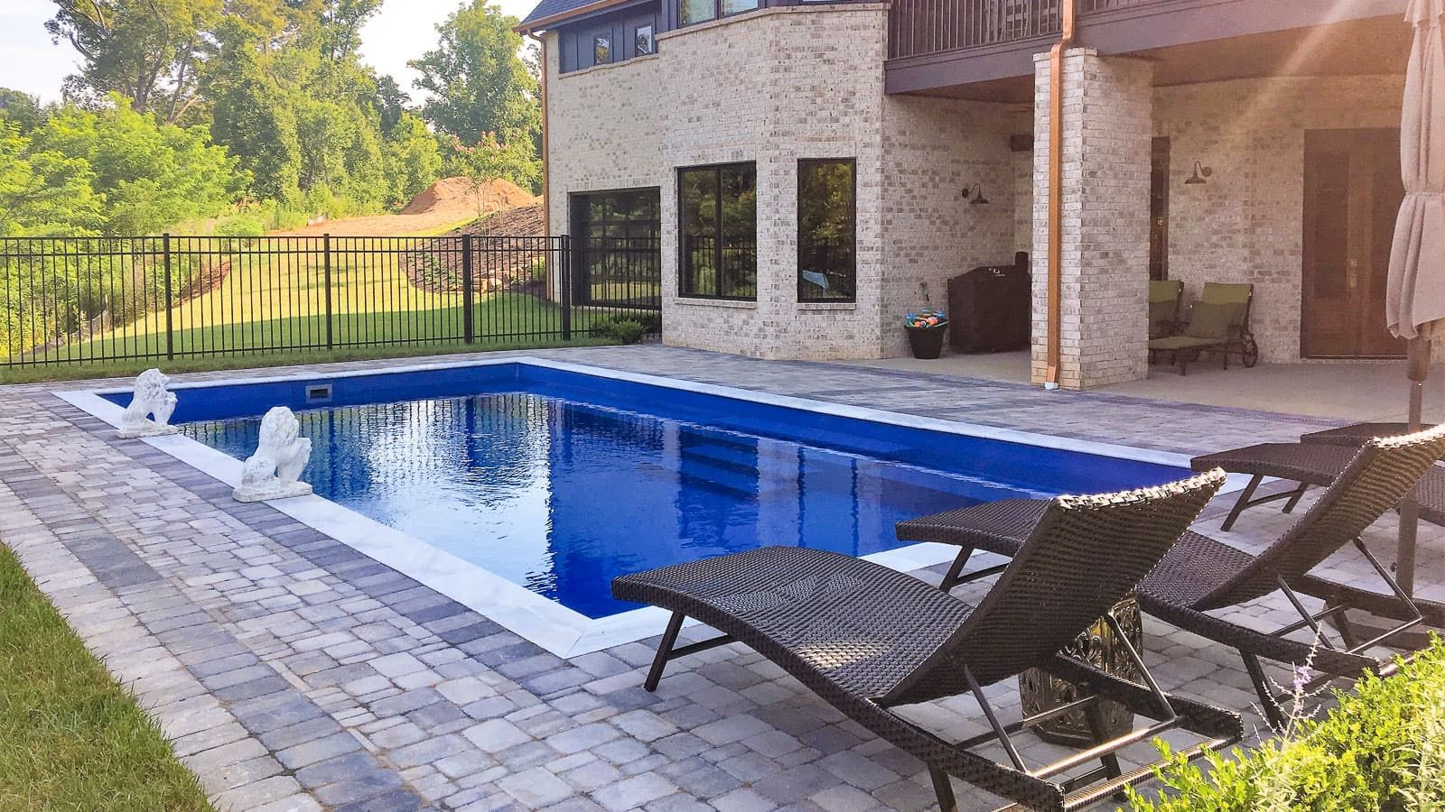 There is a large swimming pool in the backyard of a house.