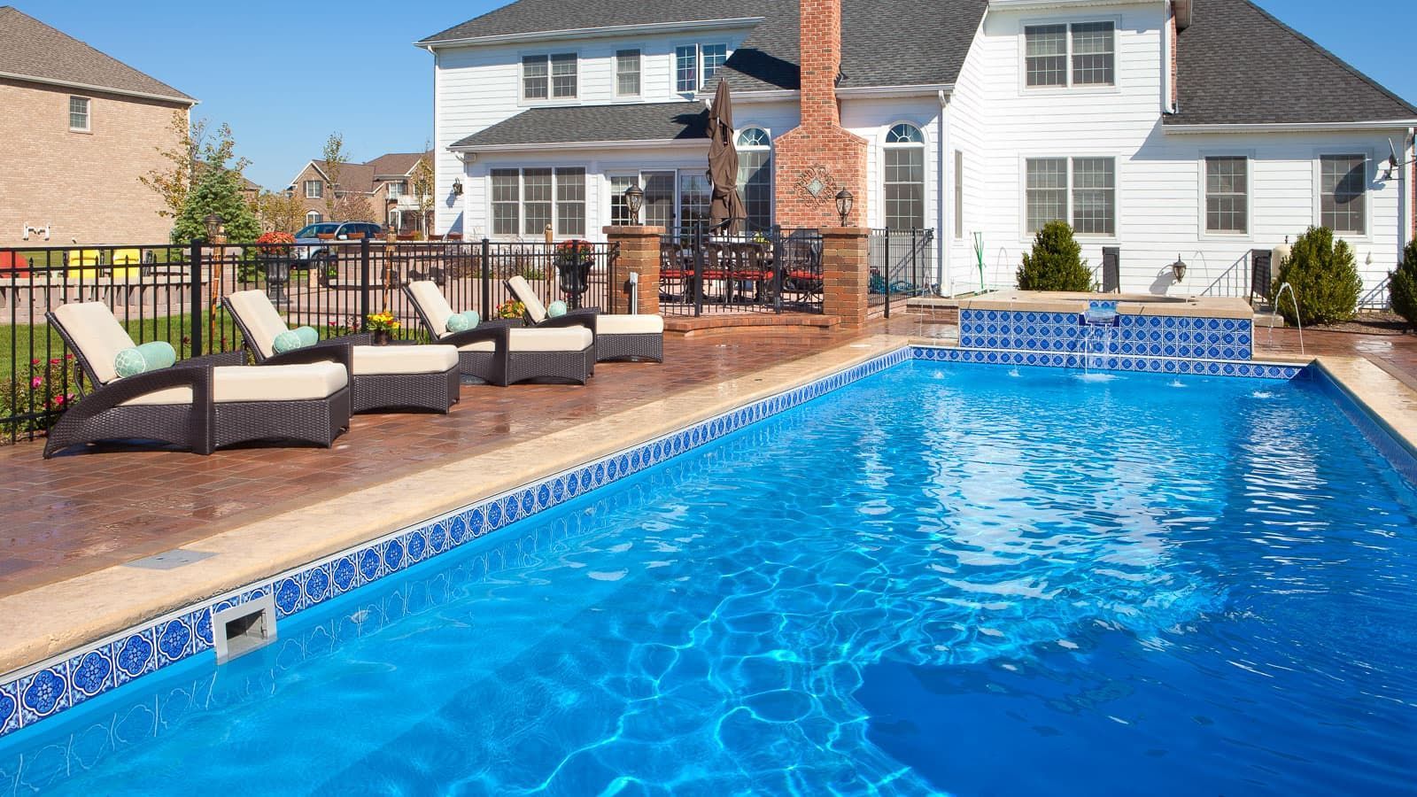 A large swimming pool is in the backyard of a house