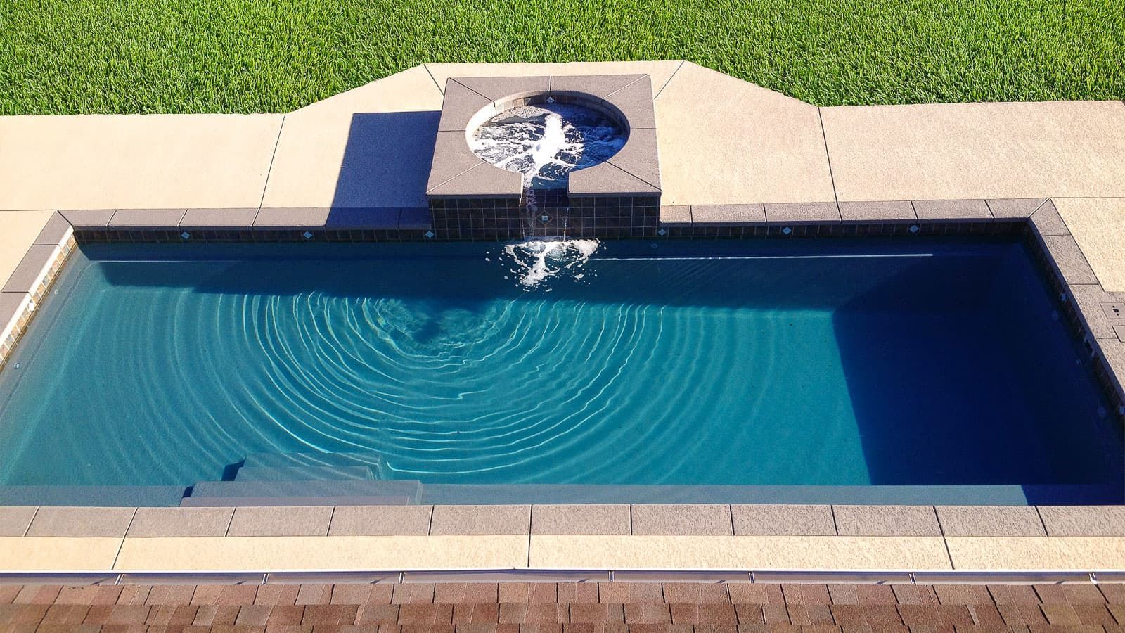 A swimming pool with a fountain in the middle of it