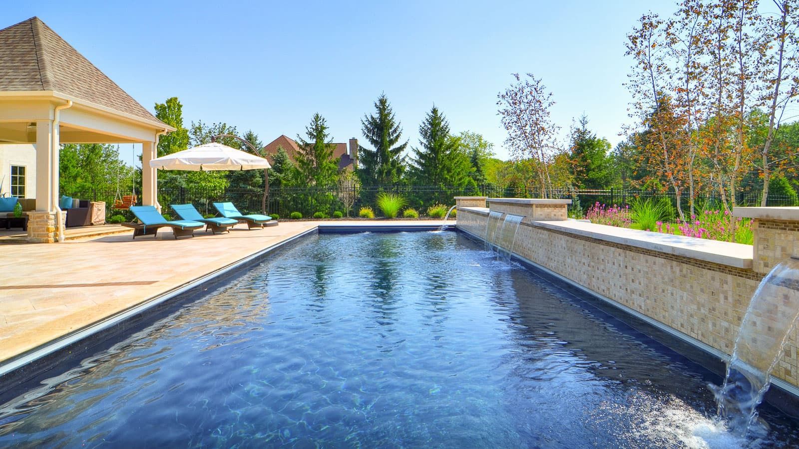 There is a large swimming pool with a waterfall in the middle of it.