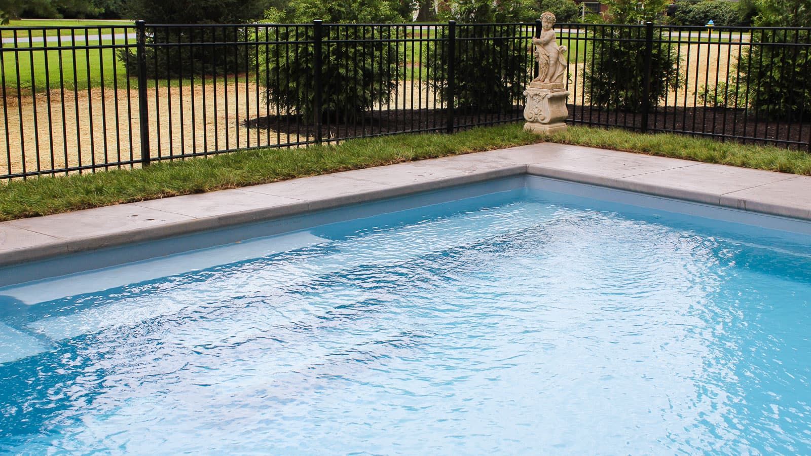A large swimming pool with a black fence surrounding it.