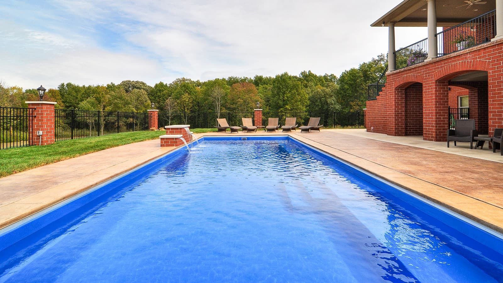 There is a large swimming pool in the backyard of a house.