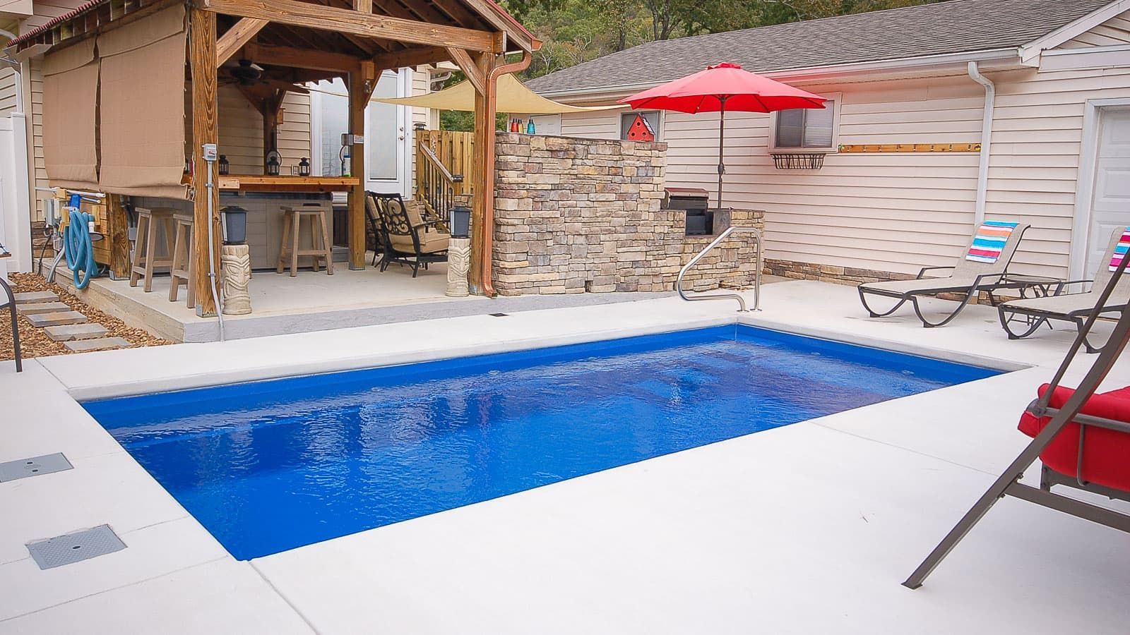 There is a large swimming pool in the backyard of a house.