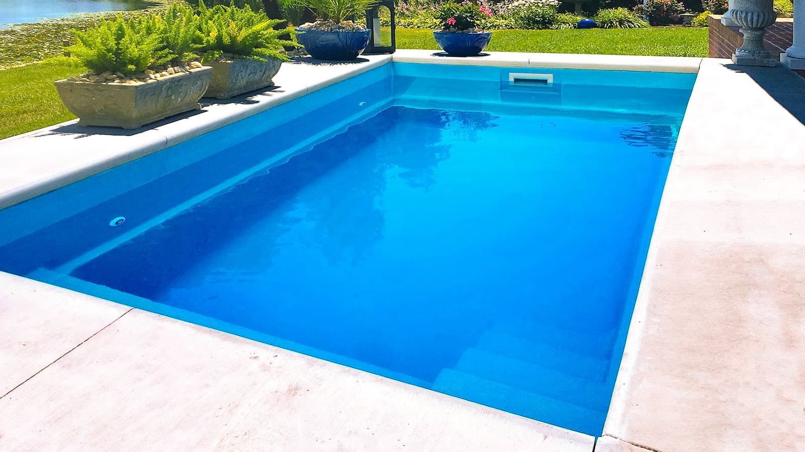 A large blue swimming pool is surrounded by potted plants.