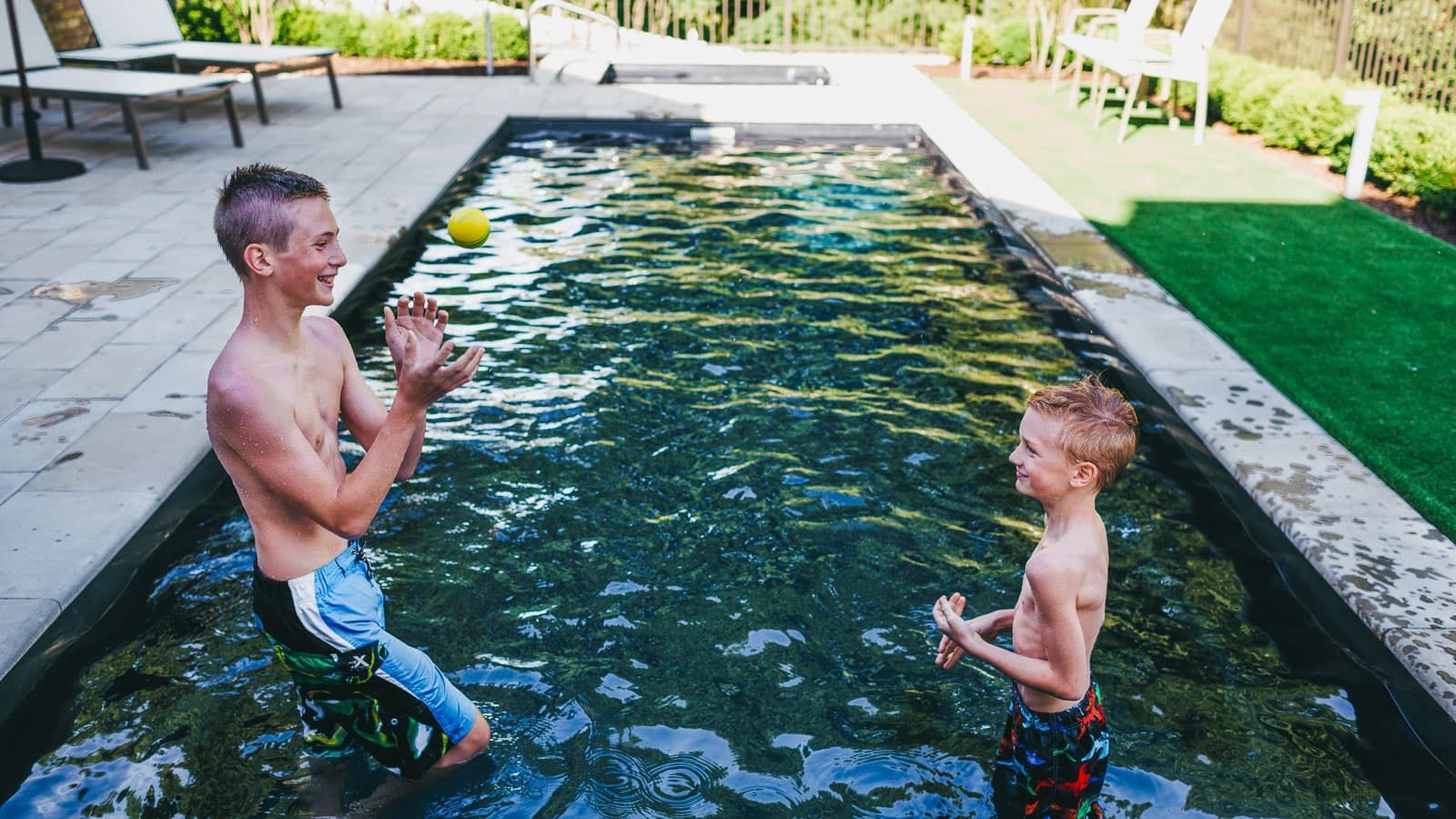 A man and a boy are playing with a ball in a swimming pool.