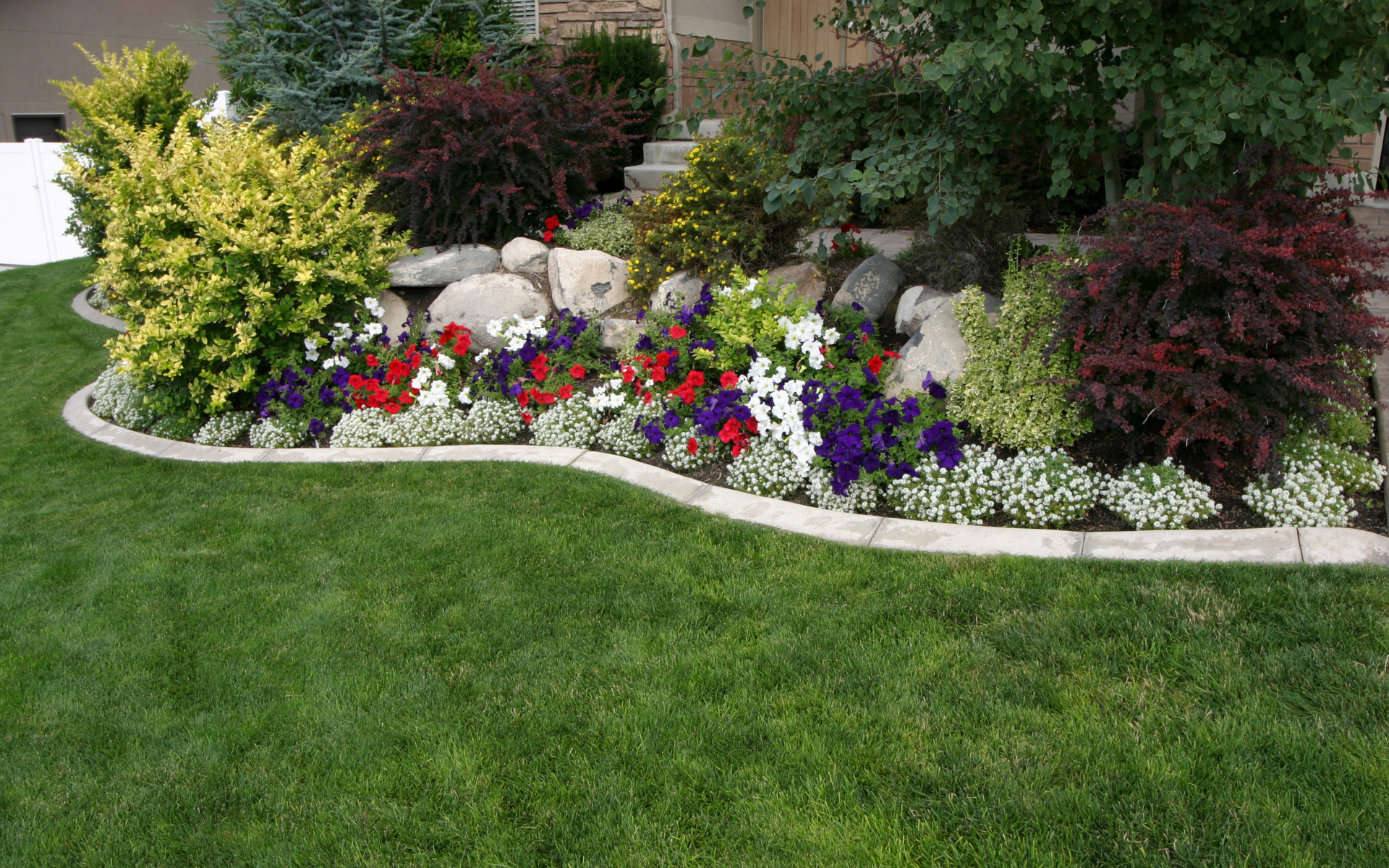 Gorgeous garden with retaining wall, large lime stone rocks, and hardscaping medled with landscaping services