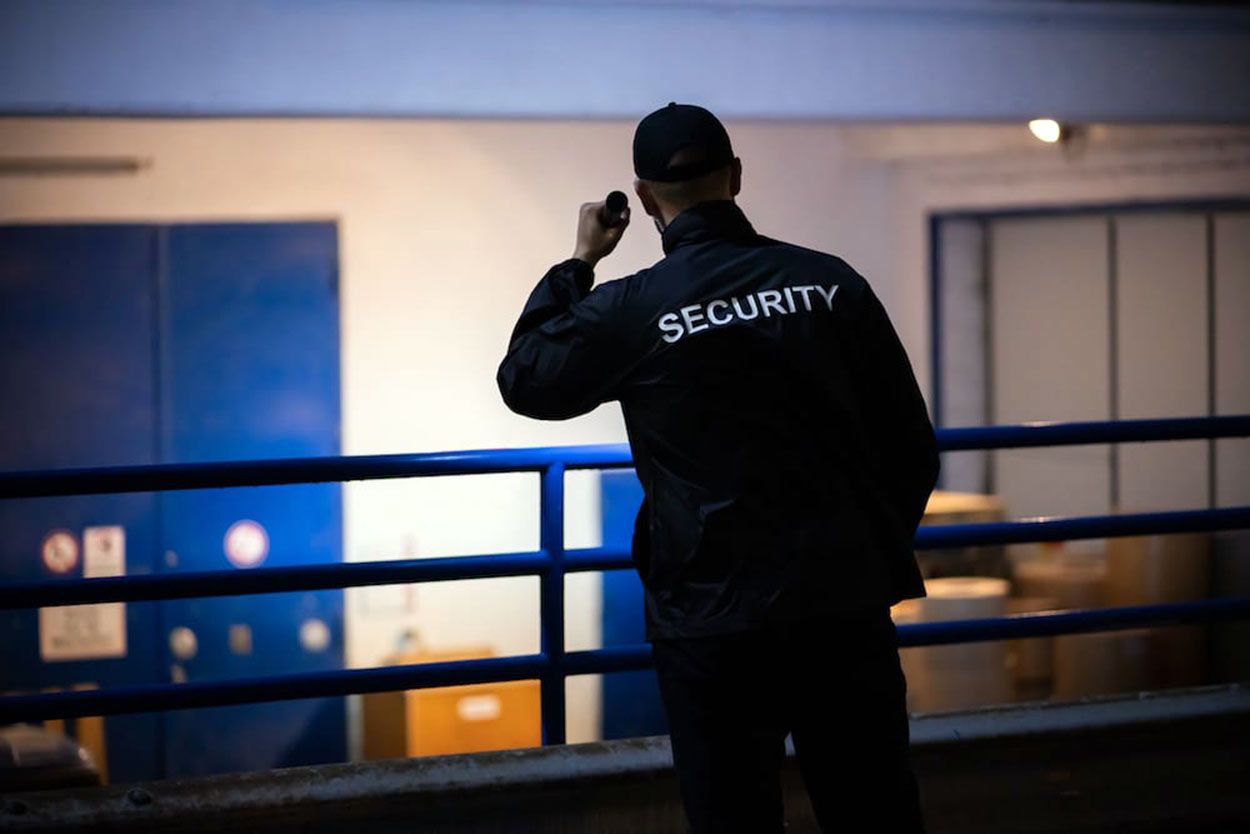 Security guard, wearing a black uniform, standing and looking out, with 