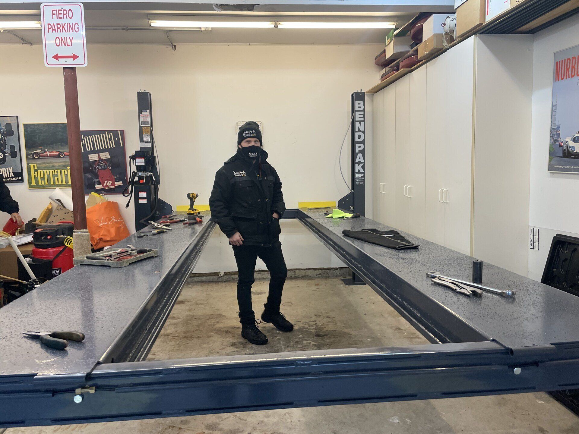 A man is standing in a garage next to a tow kart sign