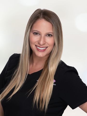 A woman with long blonde hair is wearing a black shirt and smiling.