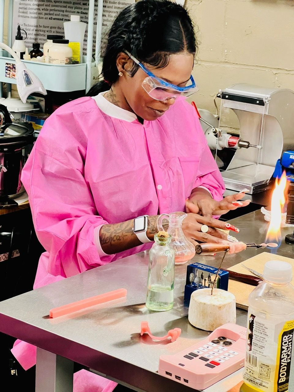 A woman in a pink gown and glasses is sitting at a table.