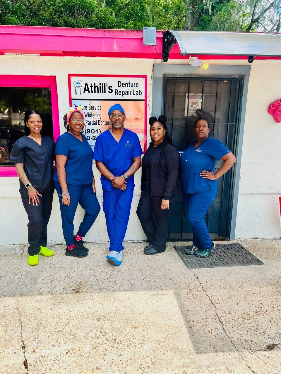 A group of people posing for a picture in front of a building that says athill 's