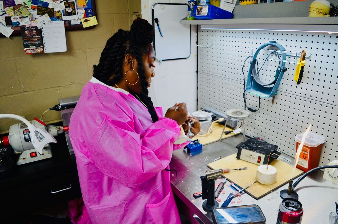 A woman in a pink gown is sitting at a table in a workshop.