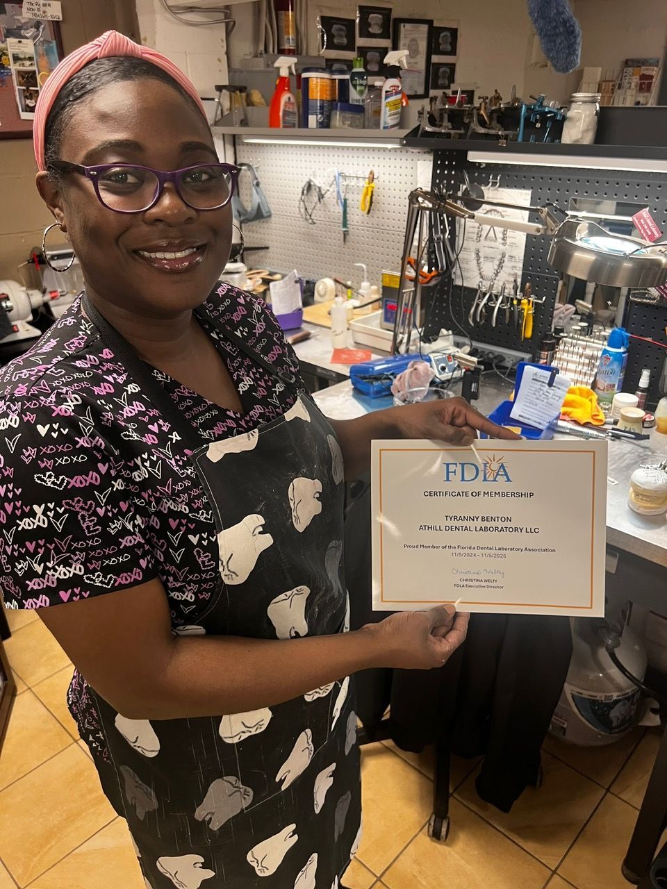 A woman is holding a certificate in a dental office.