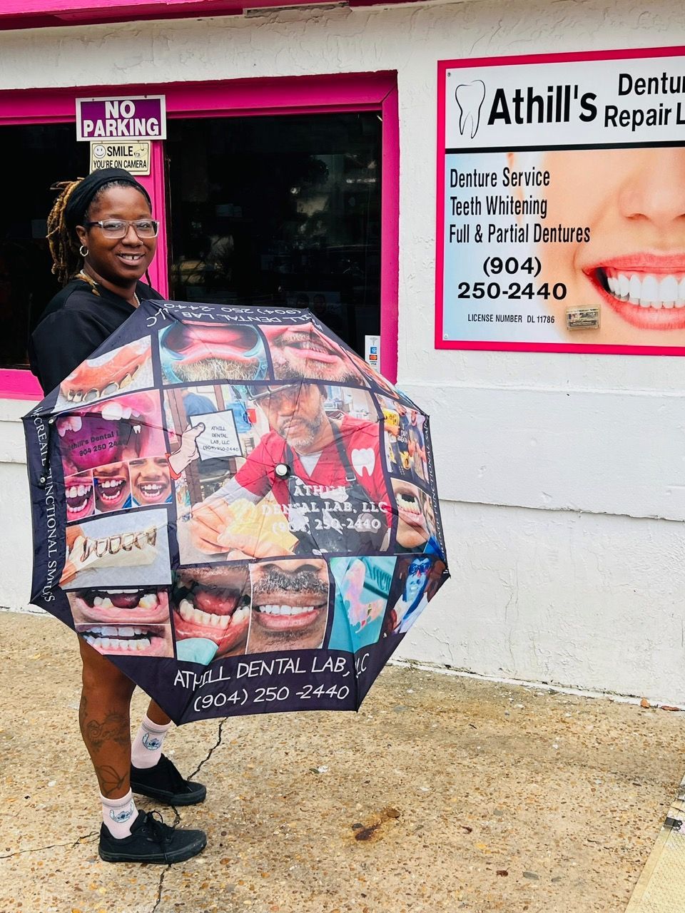A woman is holding an umbrella in front of a dental office.