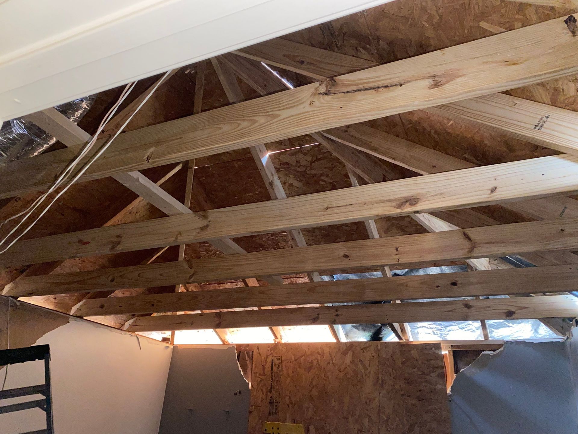 Wooden roof trusses and beams in a partially constructed room.