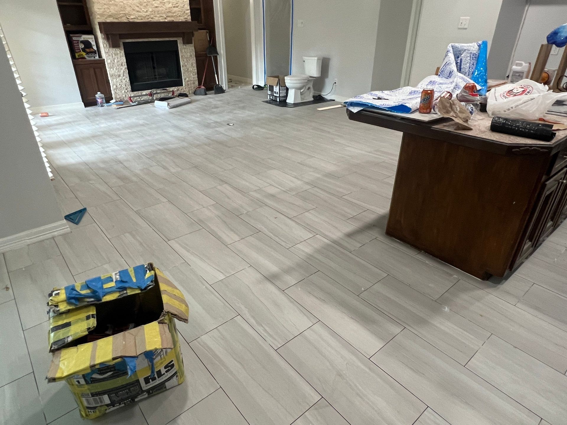 Newly tiled interior room with a fireplace and a messy table.