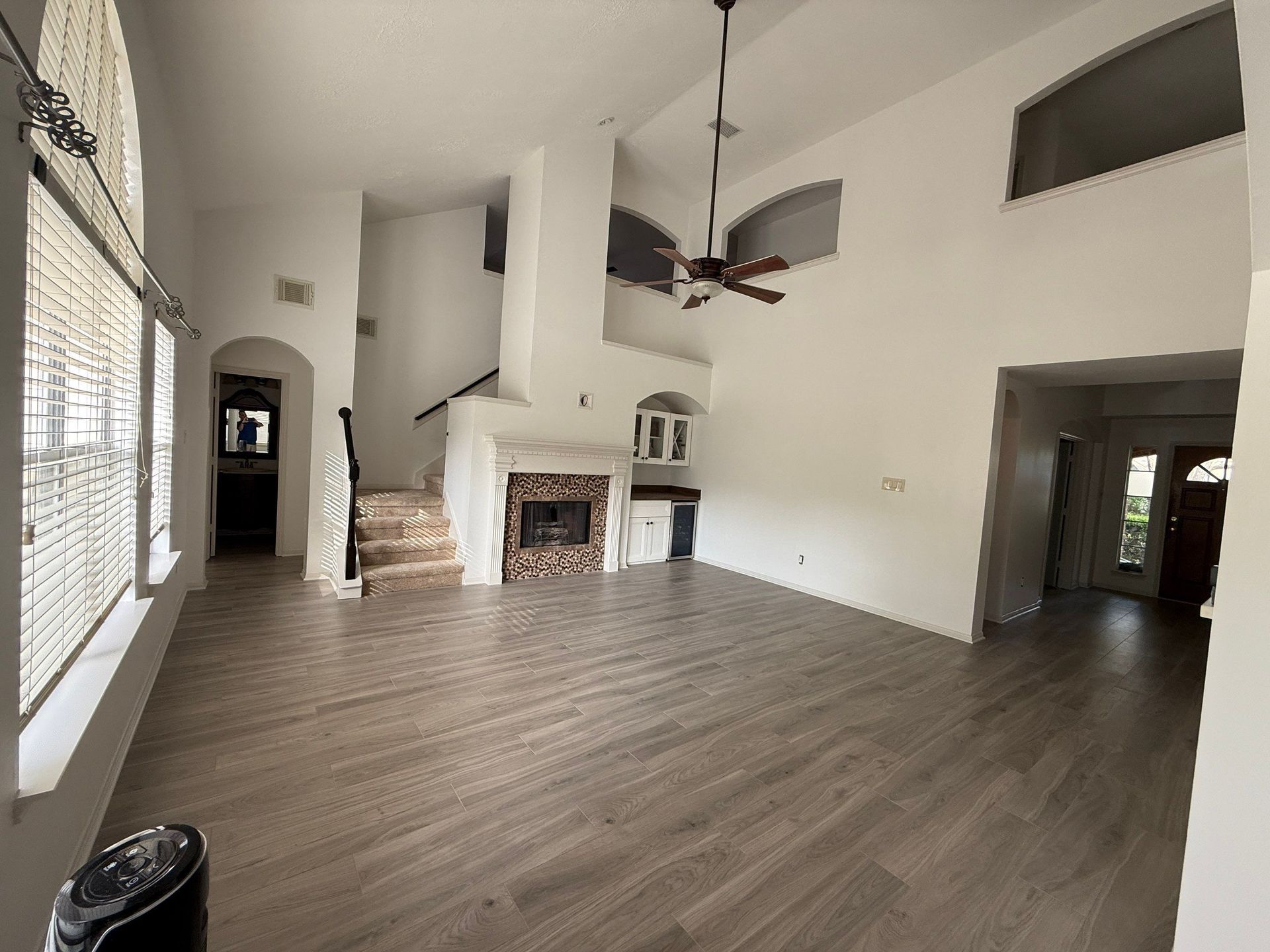 Spacious living room with hardwood floors, a fireplace, and tall windows.