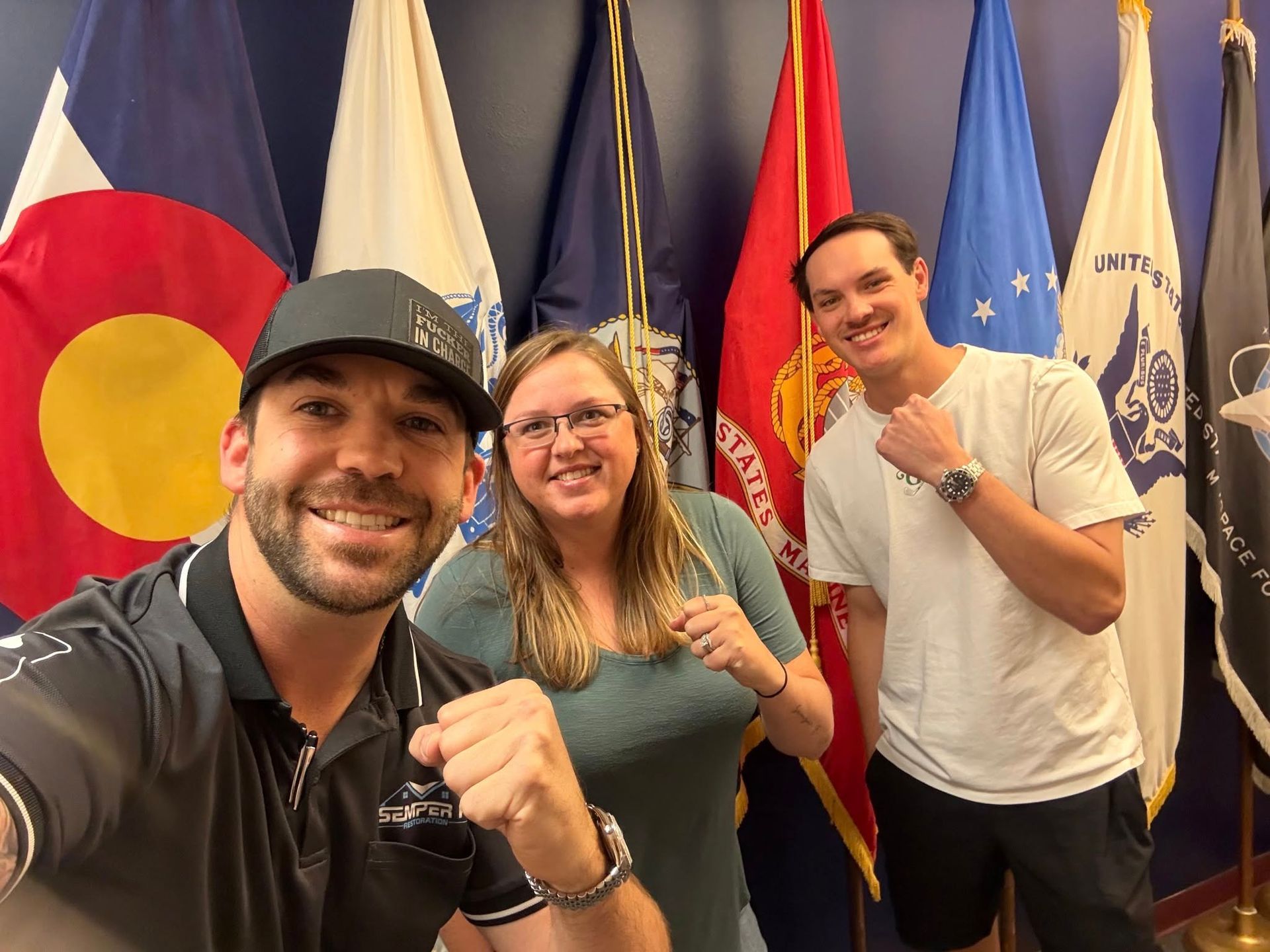 Three people are posing for a picture in front of flags.
