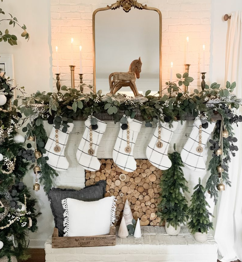 Christmas mantel decorated with greenery, stockings, candles, and a mirror. Christmas mantel decorated with greenery, stockings, candles, and a mirror.