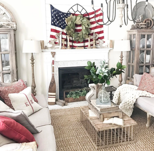 Living room with patriotic decor: American flag, wreath, fireplace, neutral tones, and wooden furniture.