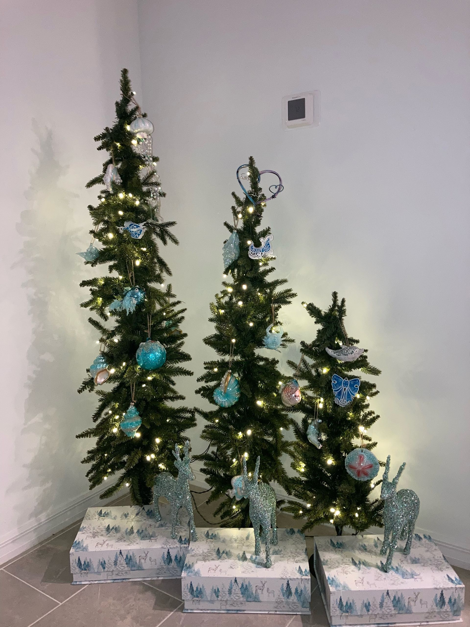 Christmas mantelpiece with silver ornaments, greenery, and white flowers, in a bright room.