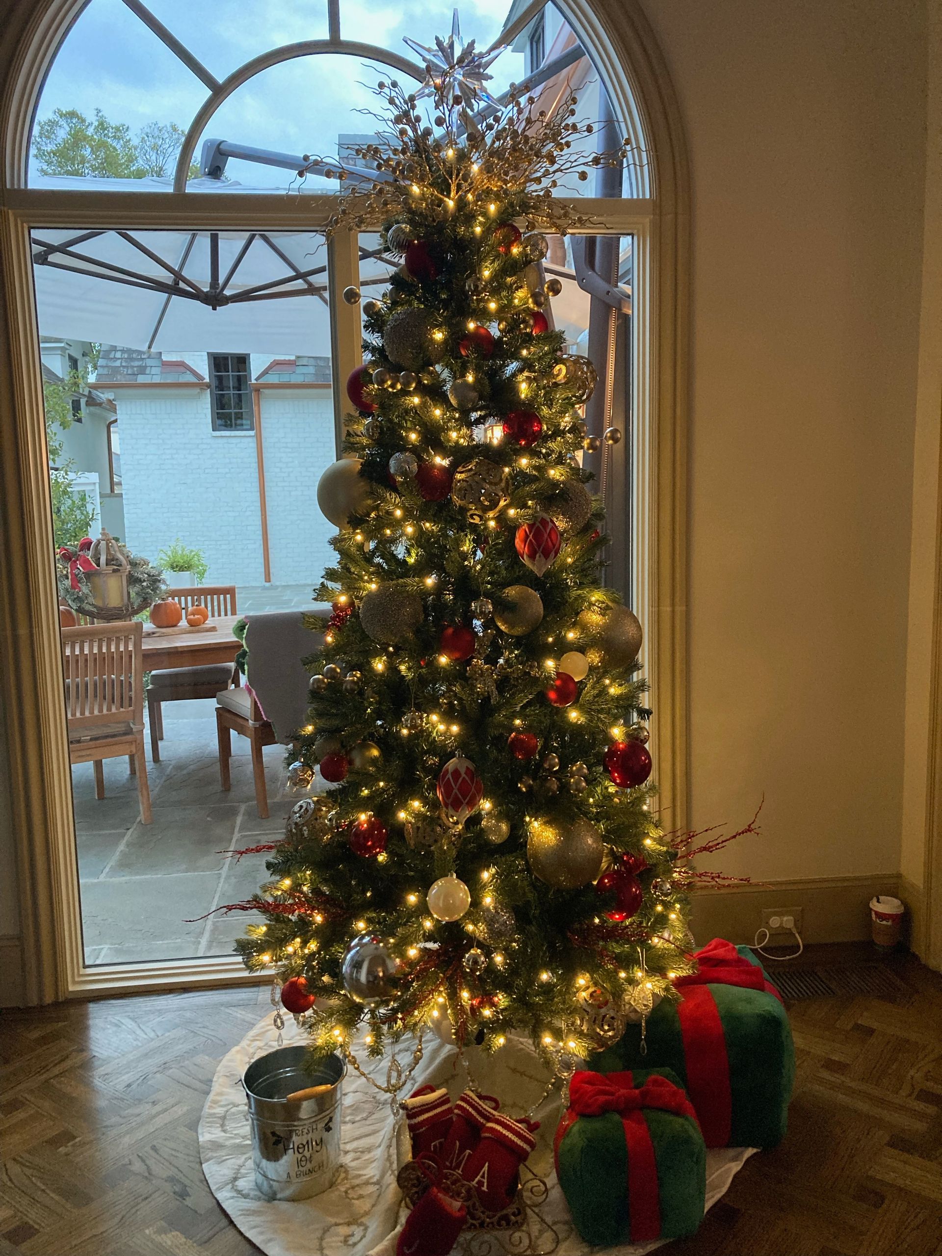 Hallway lined with decorated Christmas trees, leading to a door; gold and white lights sparkle. Hallway lined with decorated Christmas trees, leading to a door; gold and white lights sparkle.