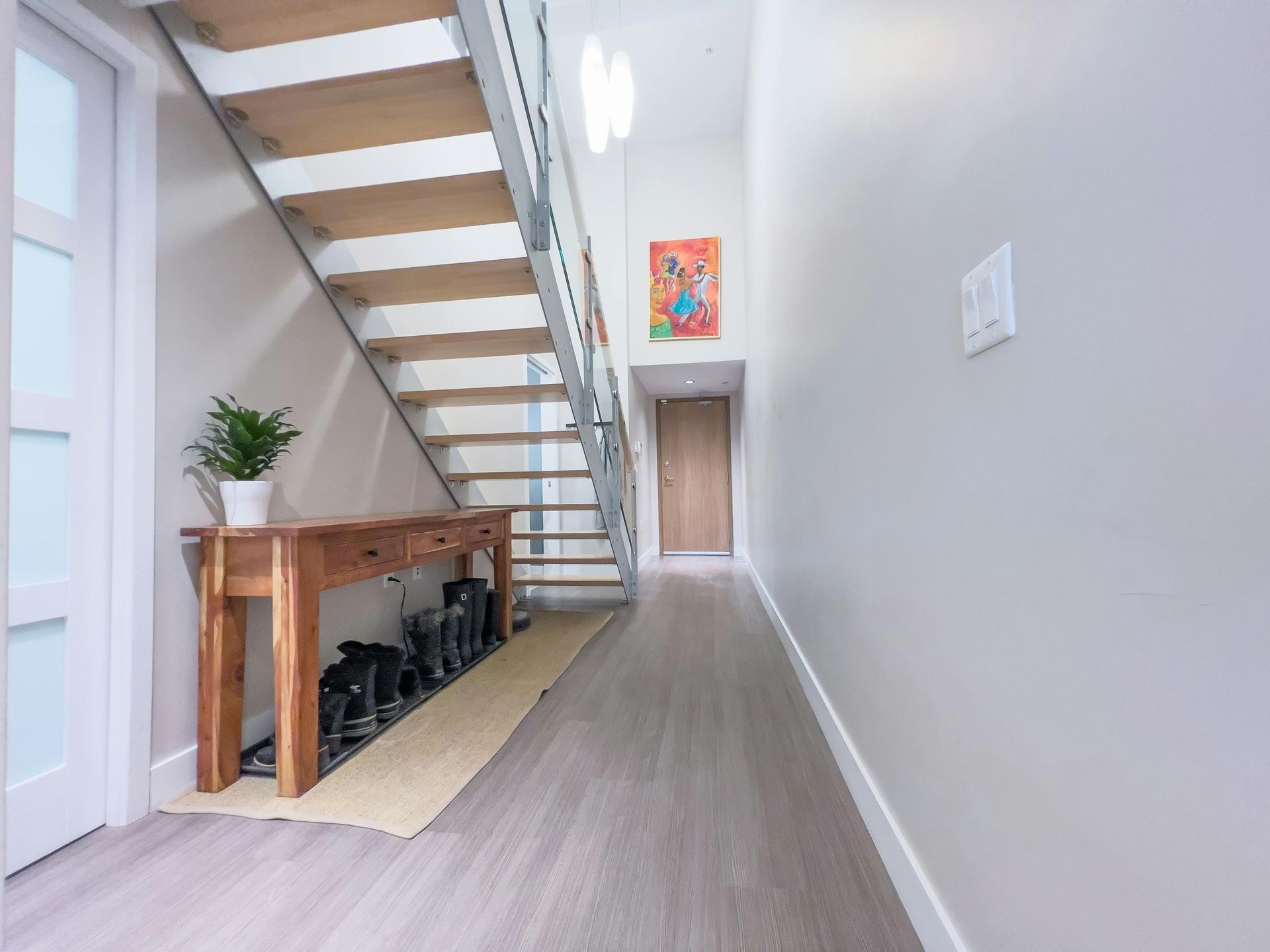 Hallway with wooden staircase, console table, and artwork on the wall.