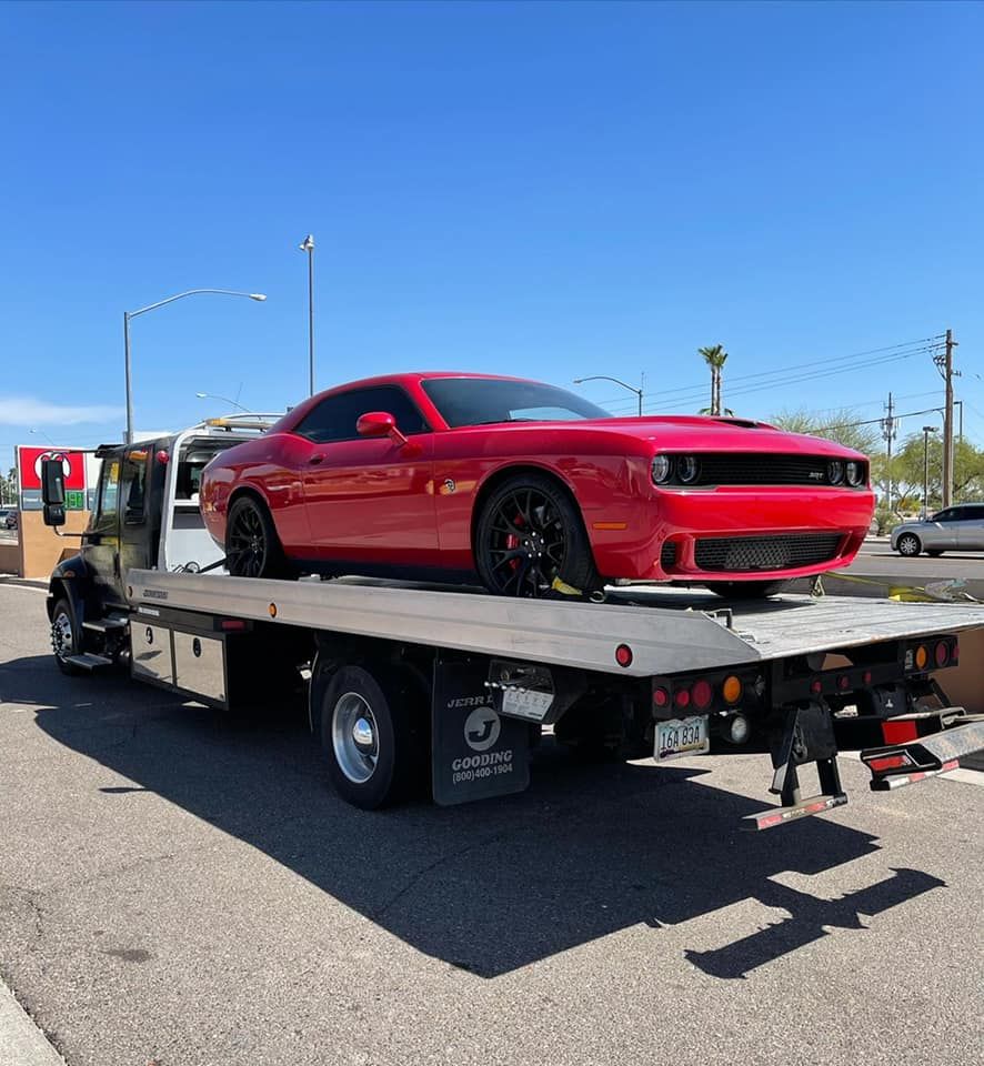 A red car is sitting on top of a tow truck.